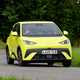 BYD Dolphin Surf (2025) review: front three quarter cornering, yellow paint, grassy B-road