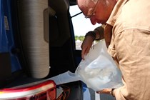 Image of a man filling a campervan water tank from a water carrier