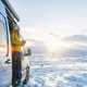 Image of man standing in the doorway of a campervan pitched in a snowy landscape