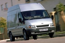 Image of a silver 2003 Ford Transit driving on an urban street, viewed from the front right corner