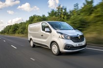 Image of a silver Renault Trafic driving on a country road, viewd from the front right corner