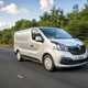 Image of a silver Renault Trafic driving on a country road, viewd from the front right corner