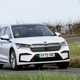 Skoda Enyaq Coupe (2024) review: front three quarter cornering, white paint, British country road, offset angle
