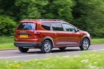 Dacia Jogger (2023) review: rear side view driving, country lane, orange paint