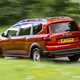 Dacia Jogger (2023) review: rear three quarter driving, country lane, orange paint