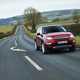 Image of a red Land Rover Discovery Sport. viewed from the front right corner while driving