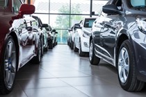 Image of two rows of cars in a showroom, looking between them from a low angle