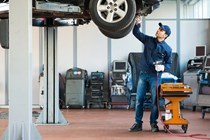 Image of a mechanic inspecting the underside of a car raised up on a lift