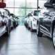 Image of two rows of cars in a showroom, looking between them from a low angle