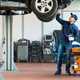 Image of a mechanic inspecting the underside of a car raised up on a lift