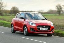 Suzuki Swift (2023) review: front three quarter driving, red paint, rural background