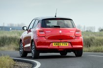 Suzuki Swift (2023) review: rear three quarter cornering, red paint, rural background
