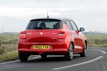 Suzuki Swift (2023) review: rear three quarter driving, red paint, rural background