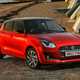 Suzuki Swift (2023) review: front three quarter static, on the beach, red paint