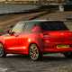 Suzuki Swift (2023) review: rear three quarter static, on the beach, red paint