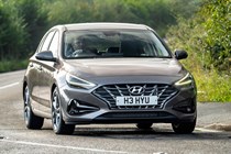 Hyundai i30 (2022) review - front cornering shot, brown car, leafy road