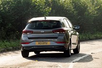 Hyundai i30 (2022) review - rear cornering shot, corner entrance, brown car, leafy road