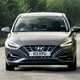 Hyundai i30 (2022) review - front cornering shot, corner entrance, brown car, leafy road