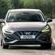 Hyundai i30 (2022) review - front cornering shot, mid-corner image, brown car, leafy road
