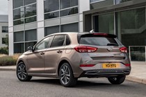 Hyundai i30 (2022) review - rear three quarter static image from passenger side, brown car, parked in front of a building