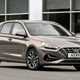 Hyundai i30 (2022) review - front three quarter static image, brown car, parked in front of a building