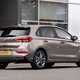 Hyundai i30 (2022) review - rear three quarter static image, brown car, parked in front of a building