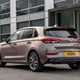 Hyundai i30 (2022) review - rear three quarter static image from passenger side, brown car, parked in front of a building
