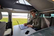 VW California review - 2019 T6.1 model, man working on laptop at interior table
