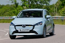 Mazda 2 (2023) review: front three quarter cornering, showing body roll, blue paint, British country road