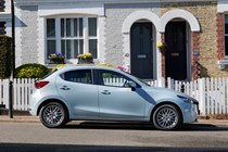 Mazda 2 (2023) review: side view static, blue paint, houses in background