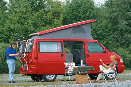 Image of Volkswagen T4 California camper van in red, set up on a camping site
