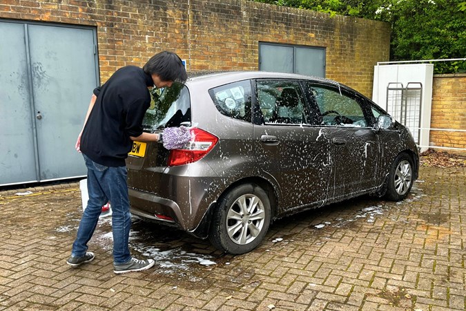 Aaron Hussain cleans a brown car to test a car shampoo