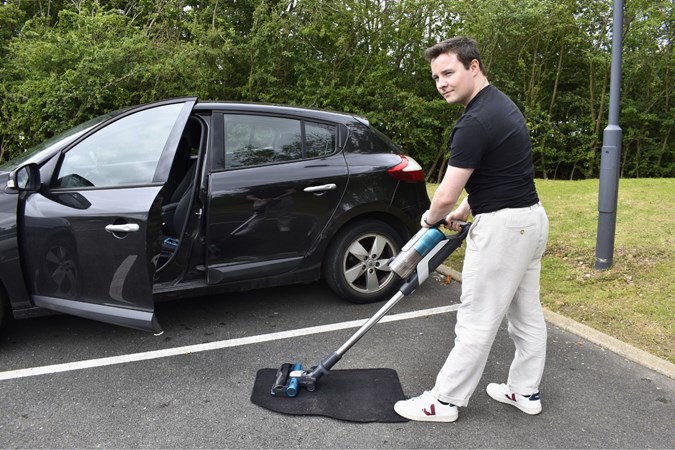 Ryan Gilmore tests a vacuum cleaner on a car mat