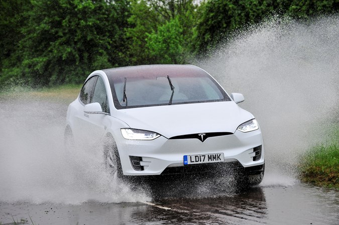 White 2017 Tesla Model X SUV front three-quarter driving through puddles