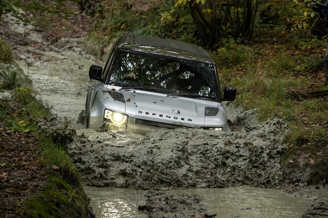 Silver 2021 Land Rover Defender 90 driving through muddy water