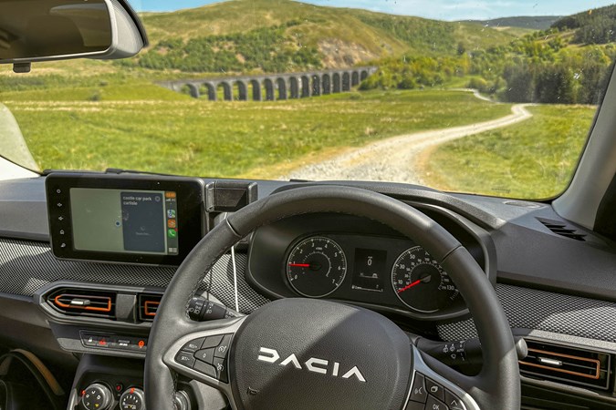 Inside a 2023 Dacia Sandero Stepway, driver's seat view across landscape