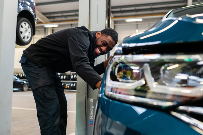 What is a car service plan? Smiling technician checking exterior of car