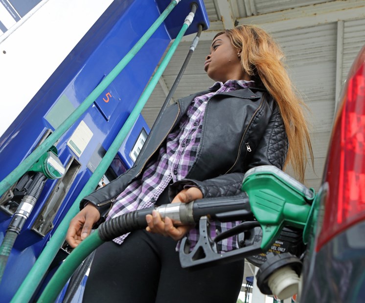 Woman using petrol pump - What is miles per gallon