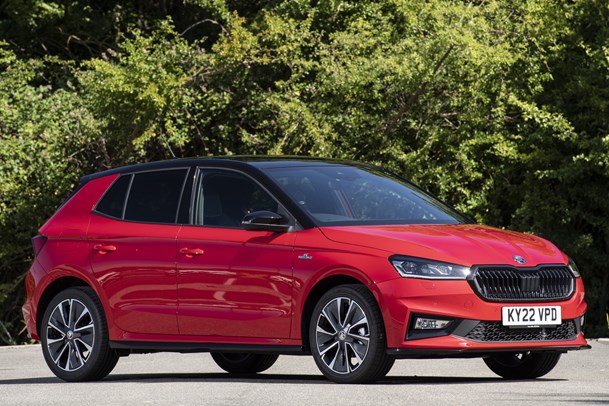 Skoda Fabia front three quarter static, red car, parked in front of some bushes