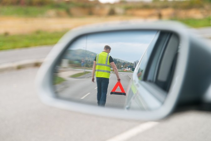 Man setting up warning triangle - Driving in Europe