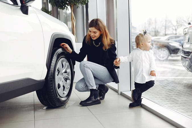 A woman with her child looking at a car in a dealership