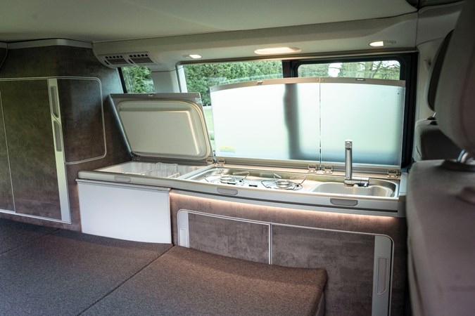 Interior of VW California, showing a sink area and fridge