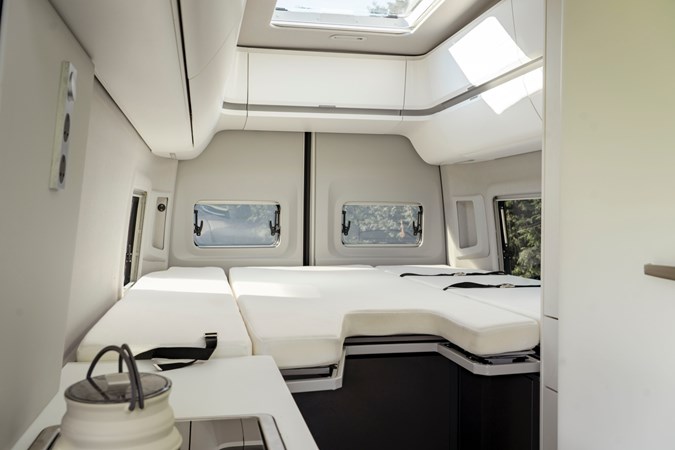 Interior shot of VW California, showing skylight window, white interior upholstery and overhead storage lockers