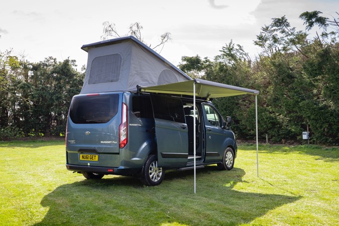 Ford Transit Nugget campervan parked on grass with roof popped and porch erected