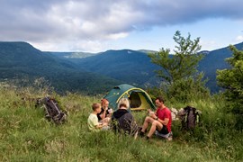 Family enjoying eating when trekking with tent in mountains