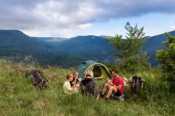 Family enjoying eating when trekking with tent in mountains