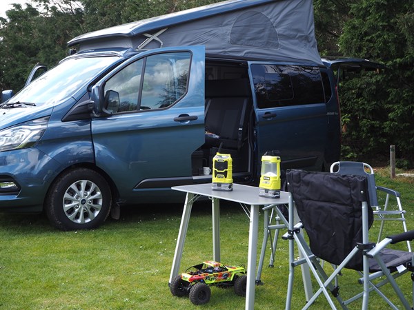 The two Ryobi camping tools near a campervan