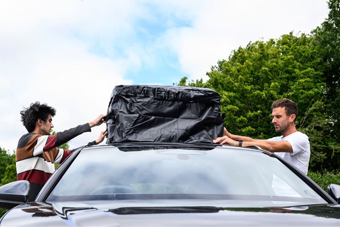 Aaron Hussain and Oli Reed mounting a roof bag to a car