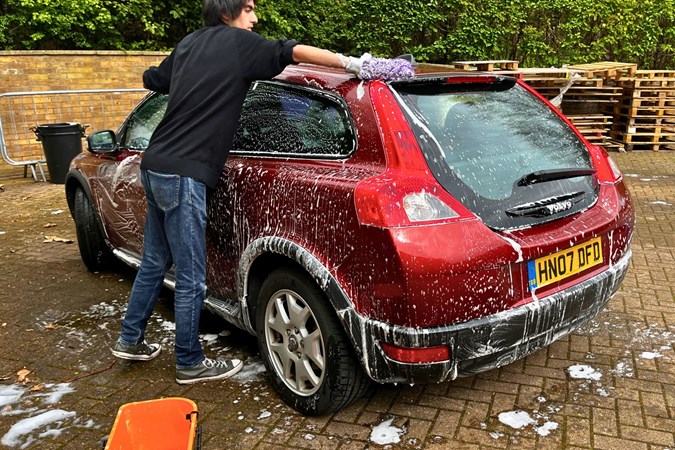 Aaron Hussain cleans a red car with a wash mitt