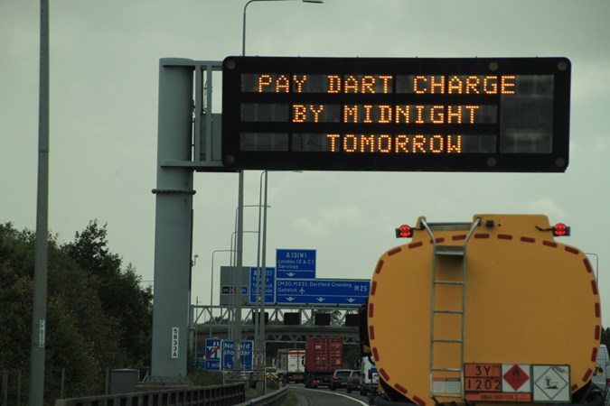 Gantry sign headlining 'Pay Dart Charge by Midnight tomorrow' in orange